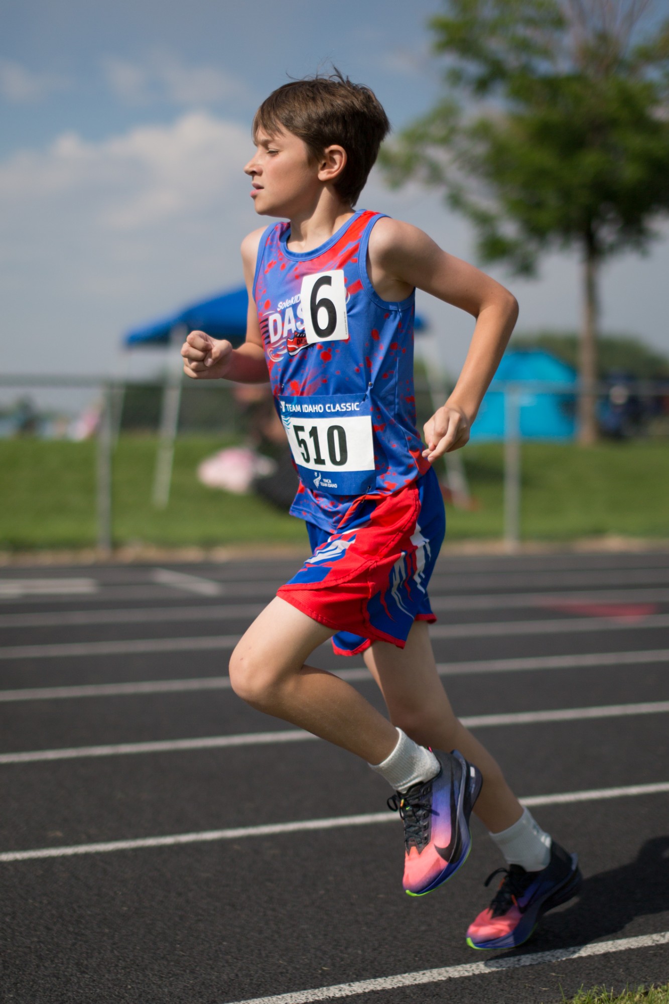 A DASH runner mid-stride on the track near parked cars